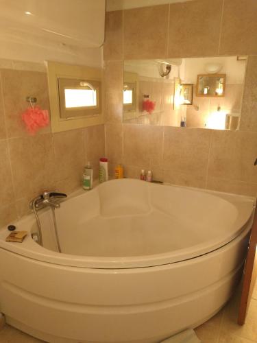 La salle de bains est pourvue d'une grande baignoire blanche et d'un miroir. dans l'établissement Le Mazet, chambre chez l'habitant, à Cagnes-sur-Mer