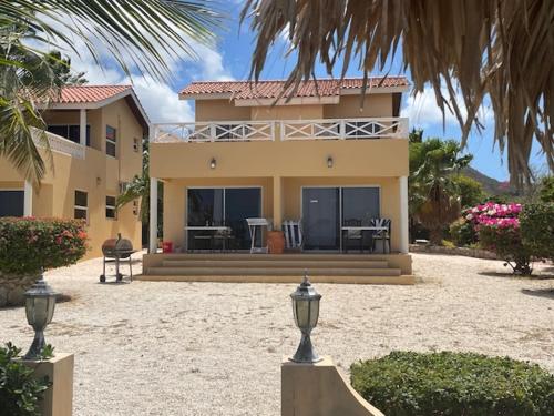 a large yellow house with a palm tree in front of it at Oceanfront apartments 18 & 19 - Lagun Blou Dive & Beach Resort, Curaçao in Lagun