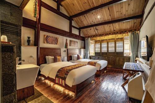 Shangrila Agedtree Hotel في شانغريلا: غرفة نوم بسريرين وحوض استحمام ومغسلة