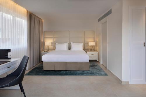 a bedroom with a large white bed and a chair at Herbert Samuel Milos Dead Sea in Ein Bokek