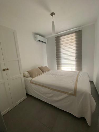 une chambre blanche avec un lit et une fenêtre dans l'établissement Appartement calme vue mer, à Sanary-sur-Mer