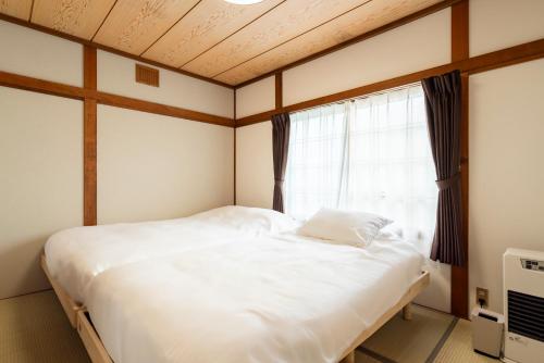 a bedroom with a large bed and a window at 雪の郷-YUKI no SATO フルリフォーム 小樽の閑静な住宅地 in Otaru