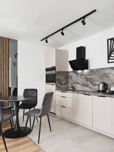 a kitchen with white cabinets and a table and chairs at Apartamenty Piast Myślibórz in Myślibórz