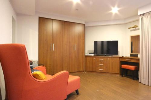 a living room with a orange chair and a television at Sky19 Hotel in Taipei