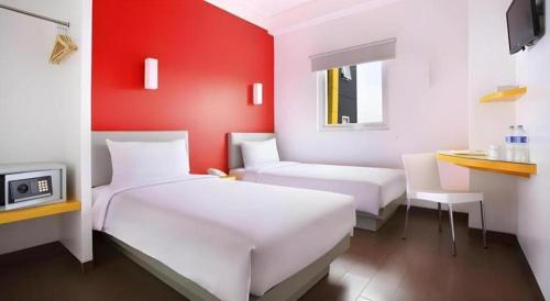 a bedroom with two beds and a red wall at Amaris Hotel Pakuan Bogor in Bogor