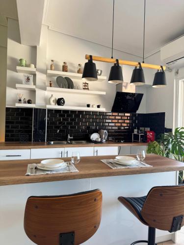a kitchen with a counter with two chairs and lights at Panoramic Seaview Blue Nest - Stylish Getaway in Amfilochía