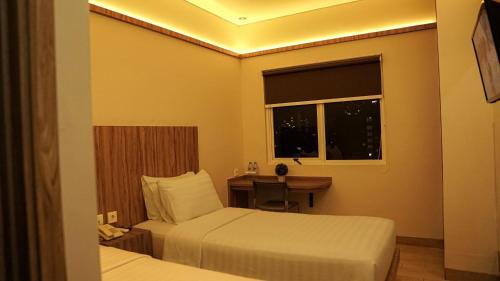 a hotel room with two beds and a desk and a window at Hotel Cikini in Jakarta