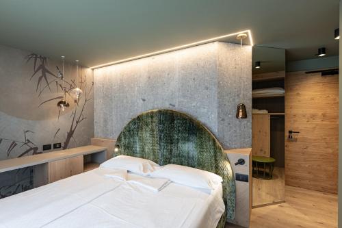 a bedroom with a large bed with a stone wall at Flos Hotel in Moena