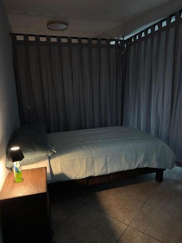 a bedroom with a bed with a curtain and a table at Habitación unos pasos de estadio GNP foro sol in Mexico City