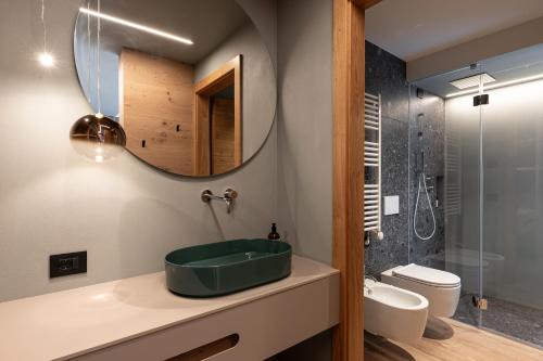 a bathroom with a green sink and a mirror at Flos Hotel in Moena