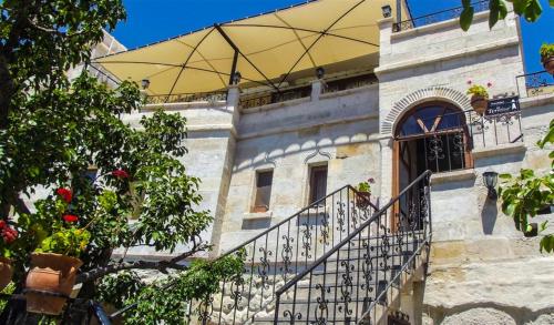 a building with a balcony and a yellow umbrella at Elysee Cave House in Goreme