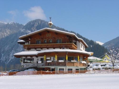 a large wooden building with snow on the ground at Hotel Gasthof Stoanerhof in Mayrhofen