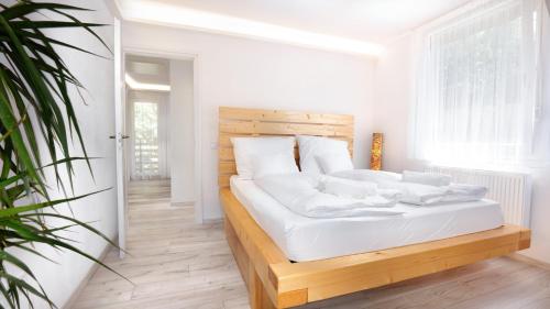 a white bedroom with a bed with white sheets and pillows at Geosun House in Salgótarján