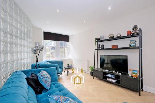 un salon avec un canapé bleu et une télévision dans l'établissement Bon Accord Square - SJA Stays - Modern 3 Bed Apartment, à Aberdeen