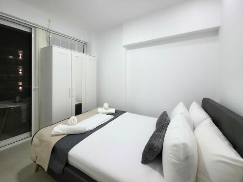 a bedroom with a bed with white pillows and a window at APOLLON Suites by SDR in Paralia Katerinis