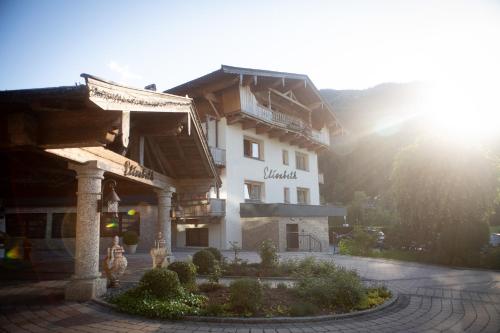 a large white building with the sun behind it at Hotel Elisabeth, 4 Sterne Superior in Kirchberg in Tirol