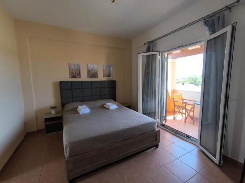 a bedroom with a bed and a balcony with a table at Aloda Summer House in Roda