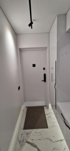 a white hallway with a door and a rug at Korsako apartamentai in Šiauliai