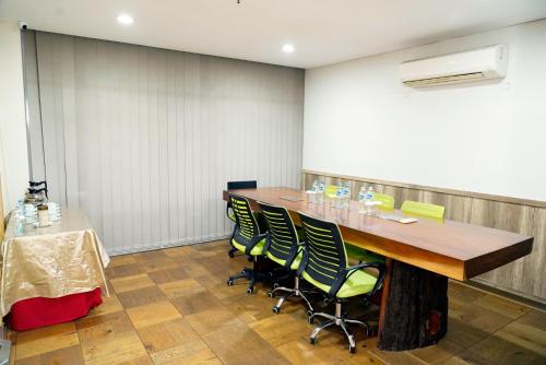 a conference room with a wooden table and green chairs at Hotel Cikini in Jakarta