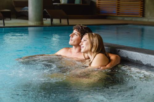a man and a woman in a swimming pool at Montresor Hotel Pfeldererhof in Pfelders