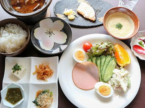 a table with a plate of food and bowls of food at ペットと泊まれる宿　孫八 in Ōichō