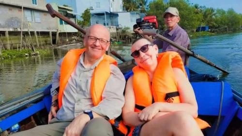 a man and a woman in a boat on the water at Dorm bed in center with balcony, rooftop and floating market tour by ADORA in Can Tho