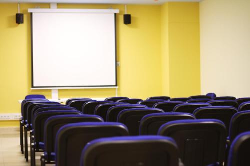 an empty lecture room with blue chairs and a screen at Hotel Reus Park in Reus