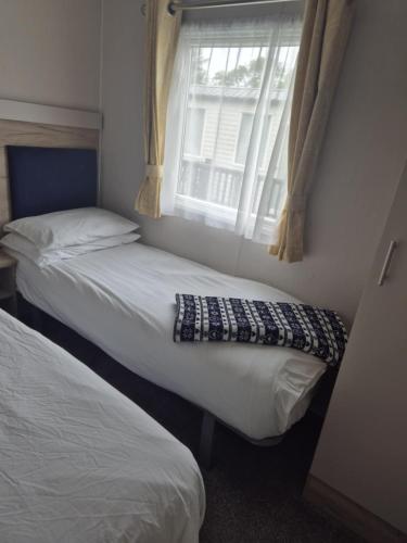 two beds in a small room with a window at Tŷ Jones Amroth Bay in Amroth
