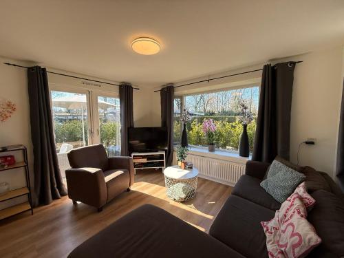 a living room with a couch and chairs and a window at Spa Chalet Veluwe Wellness with Private HOTTUB and SAUNA - Family Holiday House with Fenced Garden - Veluwe Holiday Putten in Putten
