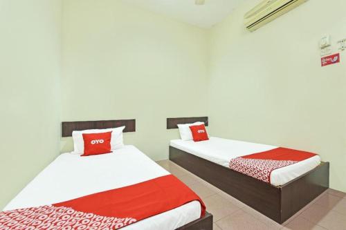 a bedroom with two beds with red and white sheets at SPOT ON 91178 Motel Impian in Seri Manjung