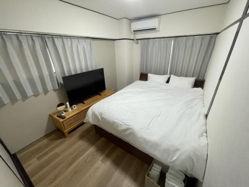 a bedroom with a bed and a flat screen tv at フロンティアコート105号室 in Nagoya