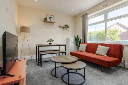 a living room with a red couch and a tv at 3 Bed Home with Free Private Parking - Contractors and Families in Little Hulton