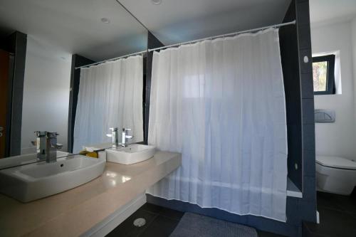 baño con 2 lavabos y cortina de ducha blanca en Vila Alvor, en Alvor