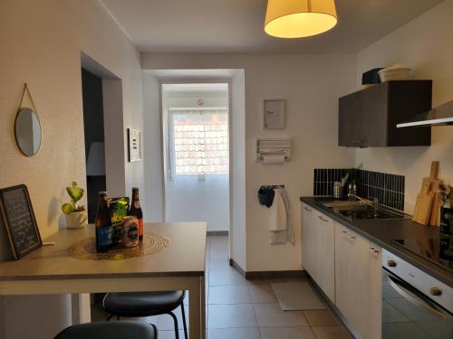 a kitchen with a table with bottles on it at Le Terramon - Appartement 4 personnes in Orbey