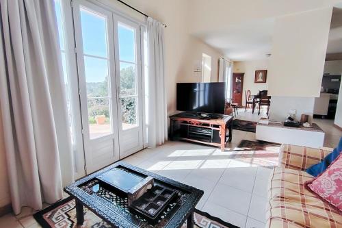 un salon avec une grande fenêtre et une télévision dans l'établissement House with AC swimming pool Garden and Carpark- BENAKEY, à Opio