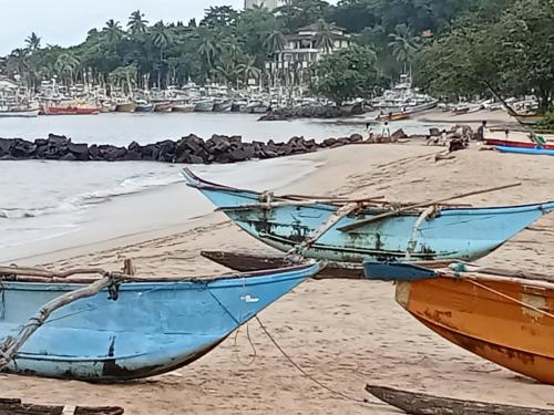 two boats sitting on a beach with the ocean at JAGA HOME in Tangalle