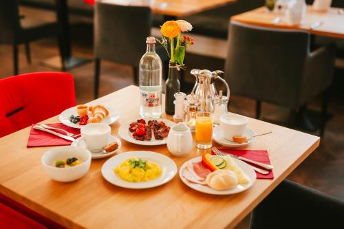 a table with plates of food and a bottle of orange juice at Post Berching in Berching