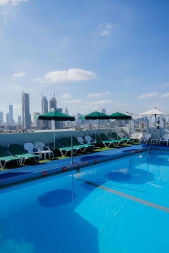 a swimming pool with chairs and umbrellas on a building at Grand Beach Hotel in Tel Aviv