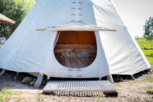 a white teepee with a bench in front of it at Briedžio sapnas in Sudervė