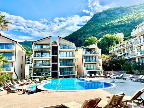 a hotel with a swimming pool and chairs and buildings at Teuta Azure Apartment - Blue Horizont Complex, Sveti Stefan in Pržno