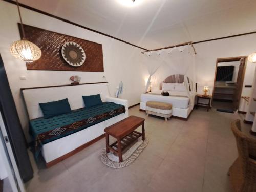 a bedroom with two beds and a table in it at Palmyra Indah Bungalows in Sekotong