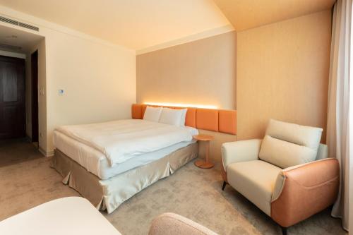 a hotel room with a bed and a chair at Hotel Tainan in Tainan