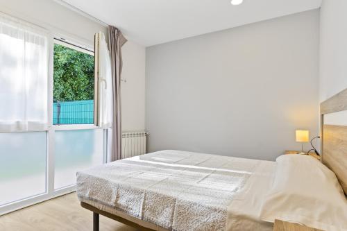 a white bedroom with a bed and a window at 2 Jardin 1 - Toró in Llanes