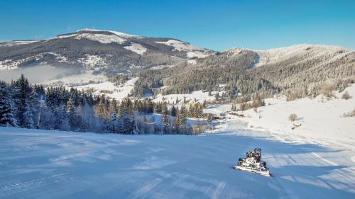 a snowmobile on a snow covered slope with mountains at Hotel Telgárt - Turistické ubytovanie in Telgárt