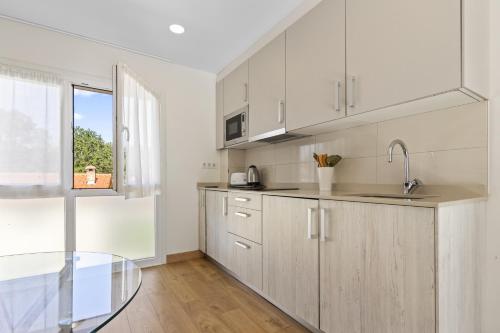 a kitchen with white cabinets and a glass table at 4 Terraza - Antilles sin jardin in Llanes