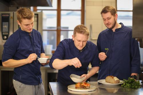 three men in a kitchen preparing food on a table at Post Berching in Berching