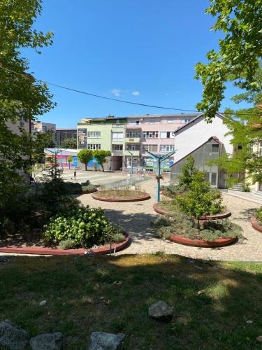 a park with trees and bushes in front of buildings at Apartments & Rooms Fountain in Bihać