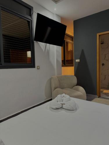 a bedroom with a bed and a chair and a television at Playa Surf House in Tamraght Ouzdar