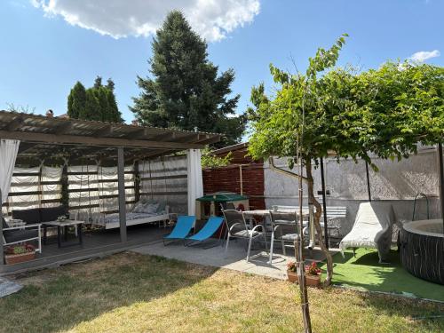 a patio with a table and chairs and a tree at Napsugár vendégház in Mezőkövesd