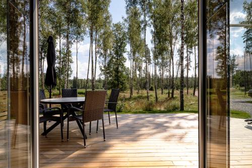 a glass door opens onto a patio with a table and chairs at Lakeville lyxigt boende mitt i skogen in Östra Målajord